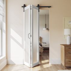 an open door leading to a bedroom with white walls and wood floors, in front of a large window