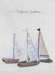 three small sailboats sitting on top of a wooden stand next to each other in front of a white background