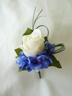 a white rose and blue flowers on a bed