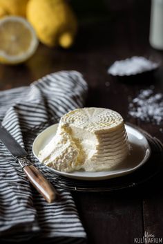 a cake on a plate next to a knife and some lemons in the background