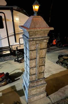 a stone pillar with a light on top in front of a camper trailer at night