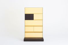 a tall yellow and black book shelf with drawers on it's sides, against a white background