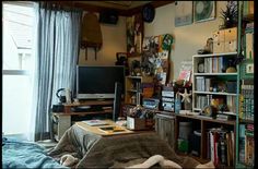 a bed room with a neatly made bed and bookshelves on the wall next to a window