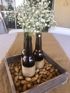 two brown bottles with flowers in them sitting on top of a table filled with nuts