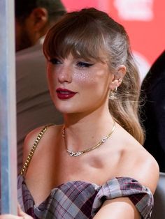 a woman with red lipstick wearing a plaid dress