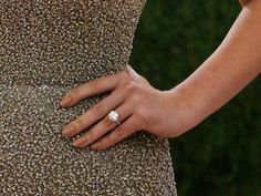 a close up of a person's hand with a diamond ring on her finger