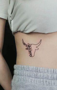 a woman's stomach with a cow and flowers tattoo on her left side belly