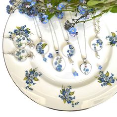 "For a well chosen 20th wedding china anniversary gift for your wife that she will always cherish, honor her with one of these exquisite broken china jewelry necklaces handmade with vintage forget me not floral china and sterling silver. Handmade from upcycled  Regency, Staffordshire, and Royal Albert china plates, each of these romantic china pendants feature the dainty blue flower known as the \"forget me not,\" which holds special symbolism. Forget me not flowers symbolize love, fidelity, and Silver Birth Flower Necklace For Wedding, Wedding Jewelry With Pressed Flowers In Silver, Silver Wedding Jewelry With Pressed Flowers, Wedding Silver Jewelry With Pressed Flowers, Valentine's Day Wedding Necklace With Birth Flower, Anniversary Jewelry With Pressed Flowers In White, Anniversary Jewelry With Pressed Flowers, White Pressed Flowers Necklace For Wedding, White Necklace For Anniversary Gift