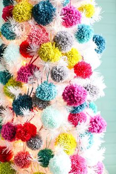 a multicolored christmas tree decorated with pom - poms