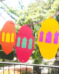 three paper cutouts hanging from a line on a clothesline with trees in the background