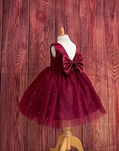 a dress on a mannequin stand against a wooden wall with a red bow