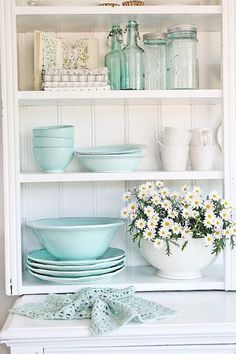 a white china cabinet filled with dishes and vases