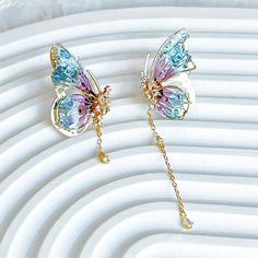 Handmade Blue Purple Butterflies with Drops Earrings These unique handmade earrings feature a beautiful butterfly wing design with purple and blue colors. The drop design adds elegance and style, making these earrings a perfect accessory for any occasion. Great for gifting, these earrings will be sure to wow. As a gift shop, we offer a complimentary gift box for every order. Some details - Size of earring: around 20mm*30mm Materials: Ear stud: gold-plated sterling silver The base of earring: resin The Handmade Blue Purple Butterflies with Drops Earrings are sold on pair of two earrings. About postage: Standard postage When choosing standard postage, we assume this order is for yourself, or you will wrap the item yourself before giving it out as a gift (the complimentary gift box would be p Handmade Blue Butterfly Earrings, Pink And Blue Butterfly, Butterfly Wing Design, Blue Butterfly Earrings, Blue Butterfly Wings, Unique Handmade Earrings, Butterfly Wing Earrings, Wing Design, Two Earrings