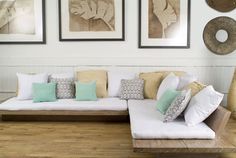 a white couch sitting on top of a wooden floor next to two framed pictures above it