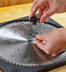 a person is using a circular saw to cut metal parts on a table with a circular saw