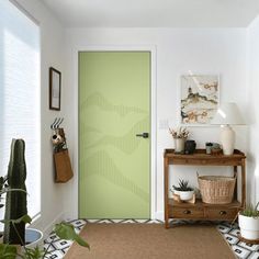 a green door in a white room with potted plants