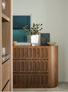 a vase with some flowers on top of a wooden cabinet