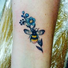 a tattoo with a bee and flowers on it