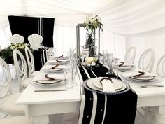 a dining table set with white chairs and place settings for six people in a marquee