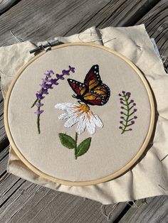 a close up of a embroidery on a piece of cloth with flowers and a butterfly