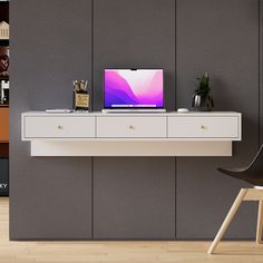 a laptop computer sitting on top of a white desk next to a chair and bookshelf