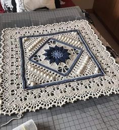 a crocheted doily with a blue and white flower on it sitting on top of a table