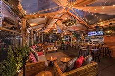 an outdoor seating area with tables, chairs and umbrellas on the roof at night