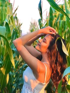 a woman standing in the middle of a corn field with her hands on her head