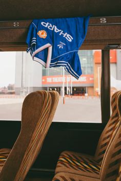 the inside of a bus with chairs and a blue jersey hanging from it's windows