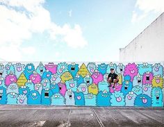 a man riding a skateboard down the side of a wall covered in cartoon characters