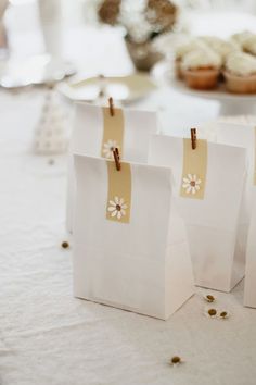 small white bags with tags on them sitting on a table next to cupcakes