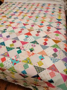 a bed with a colorful quilt on top of it