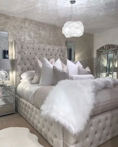 a bed with white fur on it in a bedroom next to a dresser and mirror