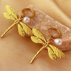 two gold dragonfly charms with pearls on them