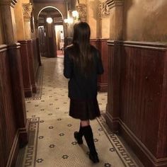 a woman walking down a long hallway in a building