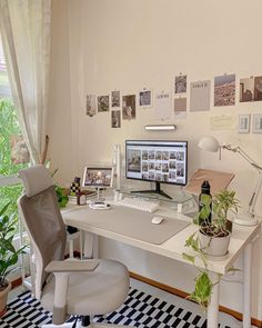 a desk with a computer, chair and potted plants on it in front of a window