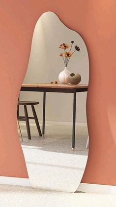 a vase with flowers sitting on top of a table in front of a mirror that is reflecting it's reflection