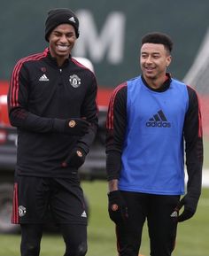 two men standing next to each other on a field with soccer equipment in the background