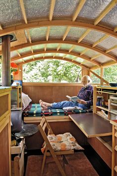 a man sitting on a bed inside of a wooden structure with shelves and desks