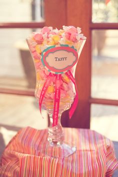 a vase filled with candy sitting on top of a table next to a sign that says taffy