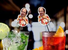 two cocktails with drinks in front of them and one has a man's face on the top