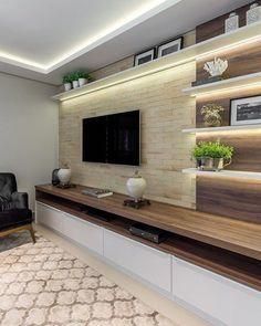 a living room with a large tv on top of a wooden shelf next to a black chair