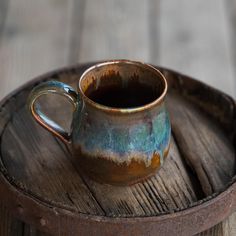 a brown and blue cup sitting on top of a wooden tray