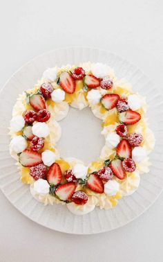 a white plate topped with a cake covered in strawberries