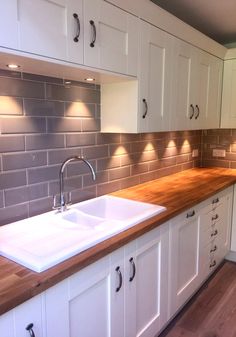 a kitchen with white cabinets and wood counter tops, along with a wooden butcher block top