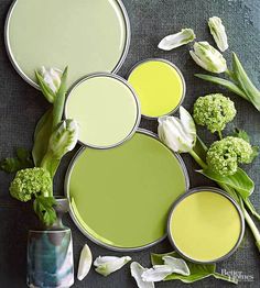 several different shades of green paint with flowers in vases on the floor next to them