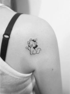 a woman's back shoulder with a small tattoo of a cat on the left side