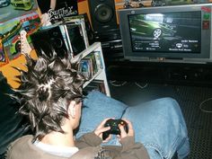 a man sitting in front of a tv holding a game controller and looking at the television