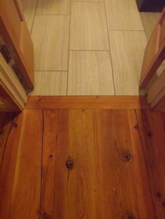 a bathroom with wooden floors and white tile on the floor, looking down at the toilet