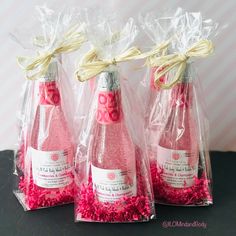 three wine bottles wrapped in plastic bags with pink confetti